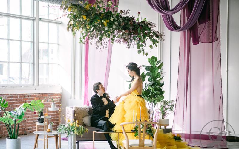 bride & groom sit under flower cloud