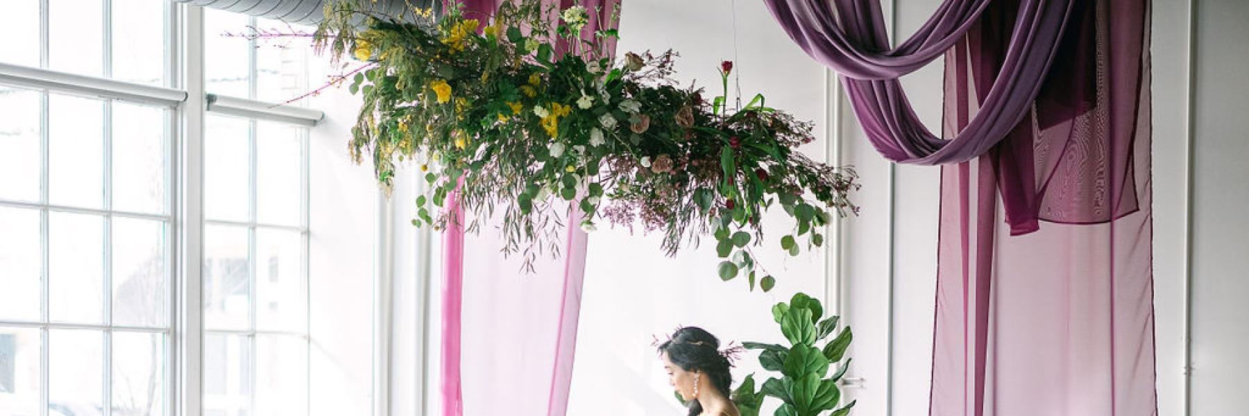 bride & groom sit under flower cloud