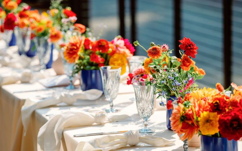 long table of colorful floral bud vases