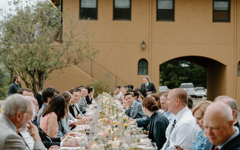 wedding guests sitting at a long dinner table 