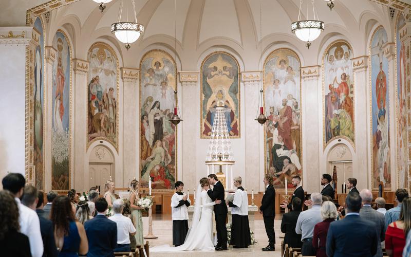bride and groom kiss at altar