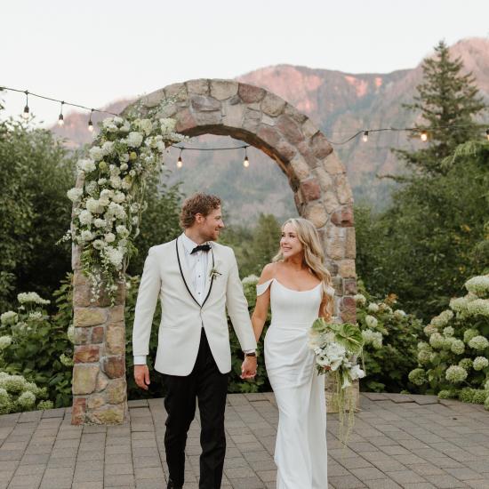 Alexa and Ryan walking in front of stone arbor