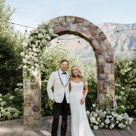 Alexa and Ryan standing in front of stone arbor